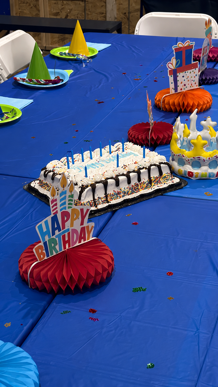 Birthday party table decorated with cakes, party hats, and a happy birthday centerpiece