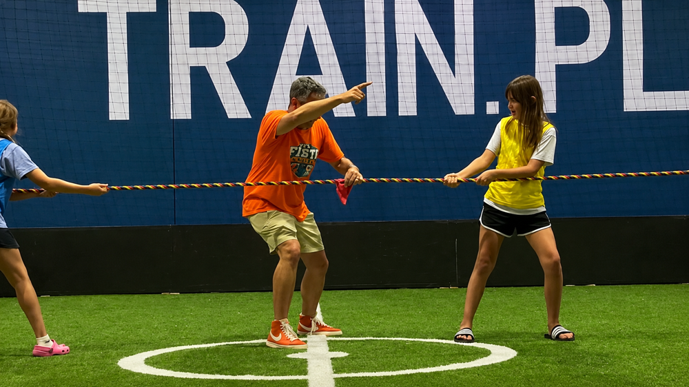 Joe leading kids in a tug-of-war game on the indoor turf field