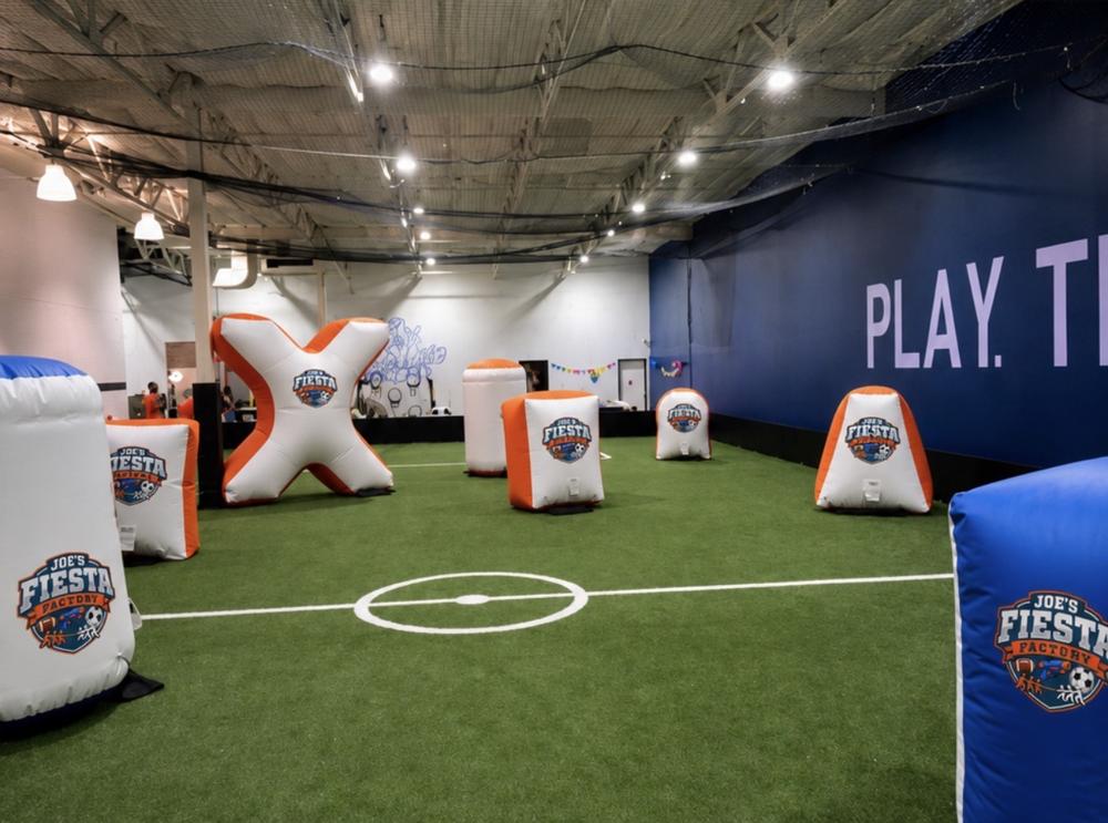 Joe's Fiesta Factory indoor turf arena with branded inflatable foam blaster obstacles