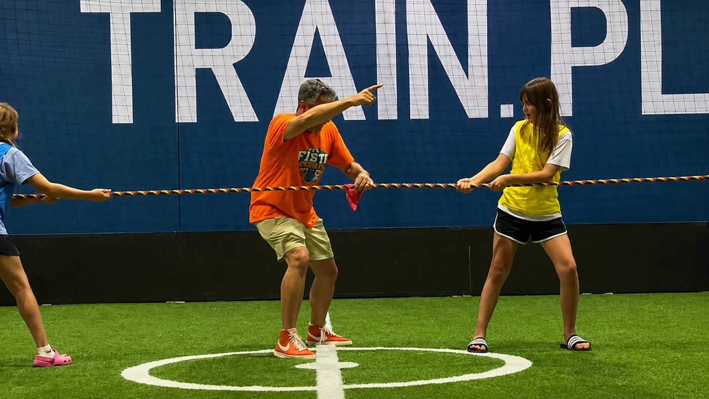 Joe leading kids in a tug-of-war game on the indoor turf field