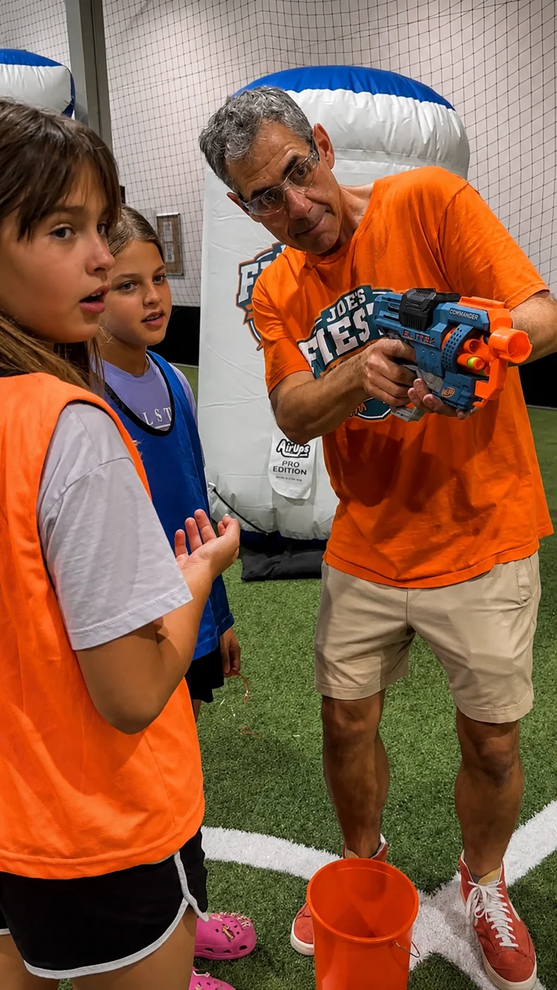 Joe showing two young party guests how to use a foam blaster safely