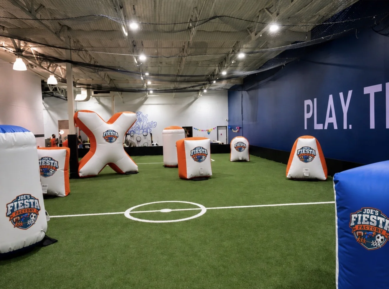Joe's Fiesta Factory indoor turf arena with branded inflatable foam blaster obstacles